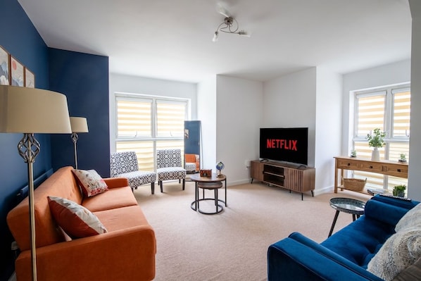 Ein Wohnzimmer mit Sofa, Sessel, Fernseher und einem kleinen Tisch.