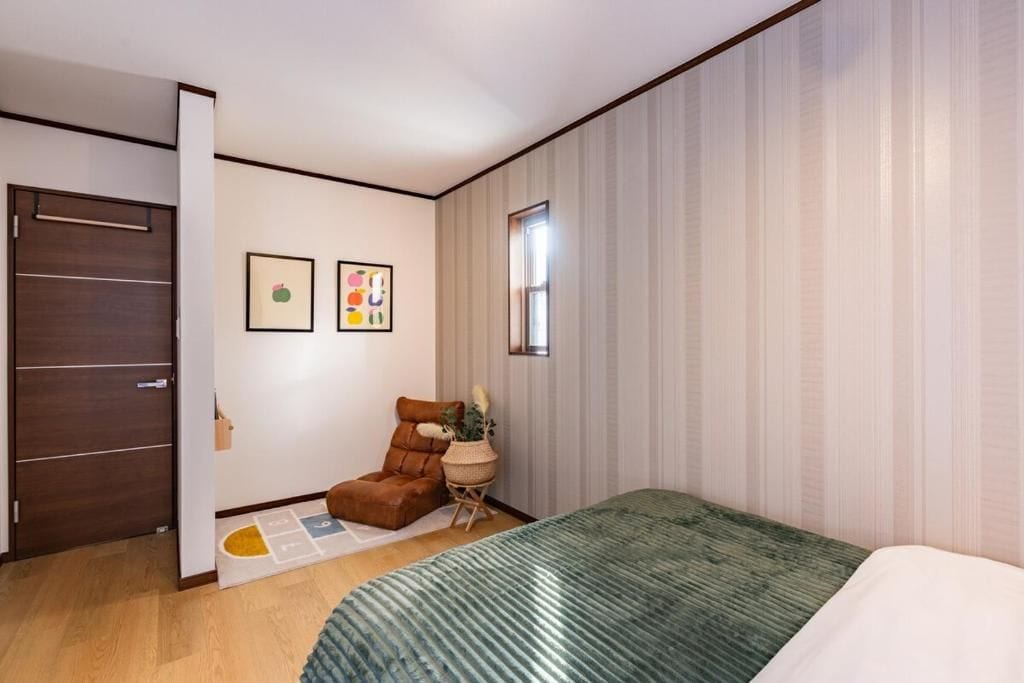 Een slaapkamer met een bed, een stoel, een klein tafeltje en een raam.