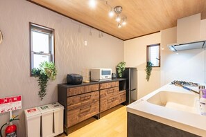 A modern kitchen with a microwave, refrigerator, and a sink. There are plants on the counter and a fire extinguisher on the floor. - NIKYO Senzo Villa Private Villa OSAKA (Osaka)