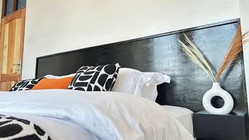 A bed with a black headboard, white bedding, and patterned pillows.