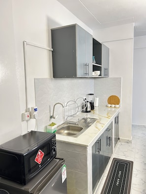 A modern kitchen with a built-in microwave, a stainless steel sink, and grey cabinets.