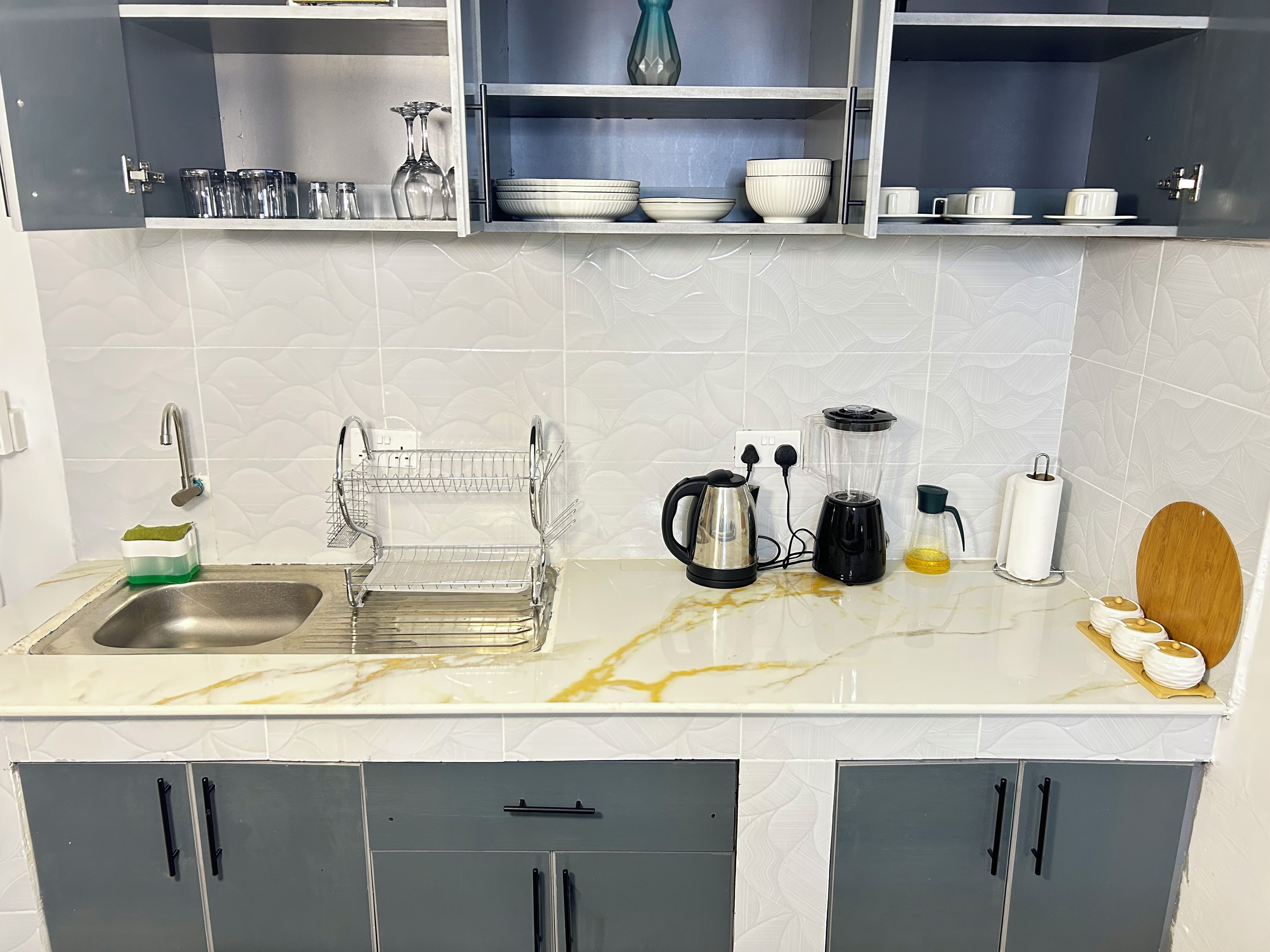 Una cocina con un lavamanos doble, un hervidor, una licuadora y una cafetera.