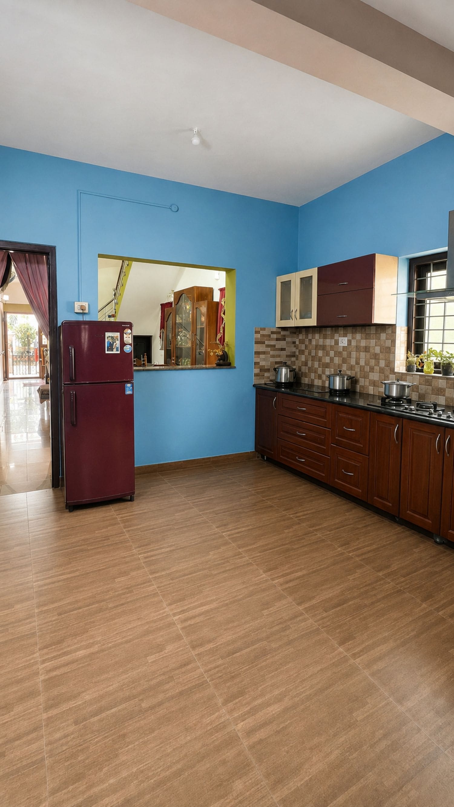 A kitchen with blue walls, wooden cabinets, and a tiled floor.