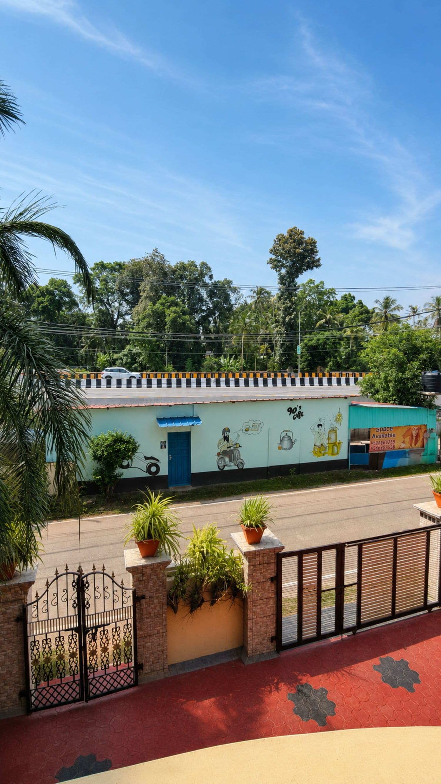 A building with a mural, a gated entrance, and potted plants.