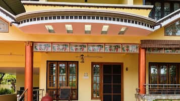A two-story building with a red carpeted entrance, a signboard with amenities, and a traditional architectural style.