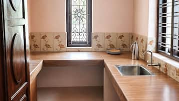 A kitchen with a wooden countertop, a stainless steel sink, and a decorative window.