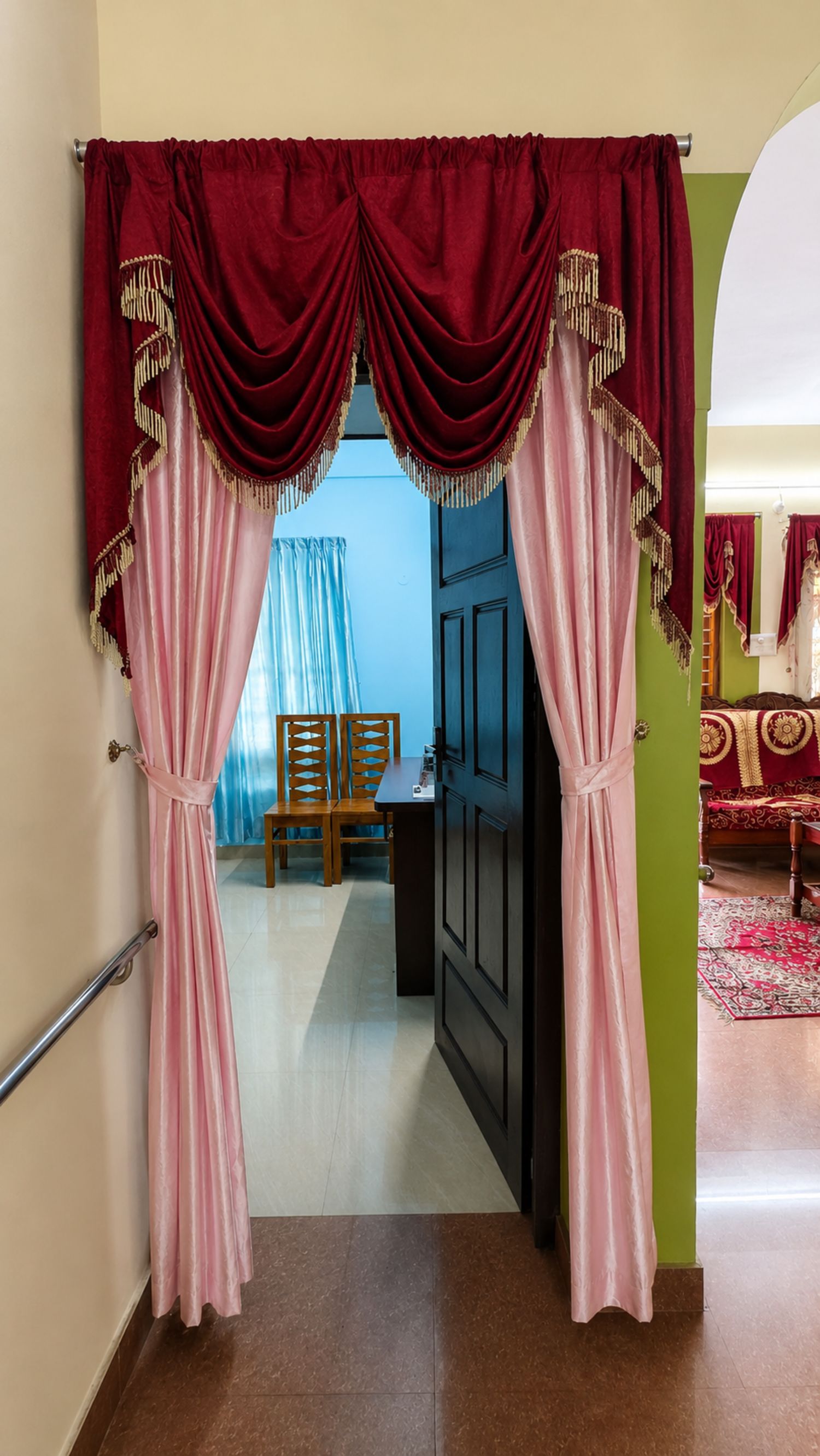 A doorway with red curtains and a glimpse of a dining area with a table and chairs.