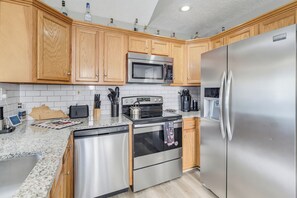 Uma cozinha moderna com armários de madeira, eletrodomésticos de aço inoxidável, micro-ondas, forno e geladeira.