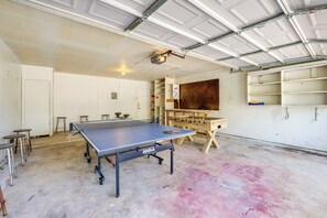 A spacious indoor area with a ping pong table, a foosball table, and a ceiling-mounted projector. - Family-Friendly Home w/ Hot Tub in San Antonio! (San Antonio)