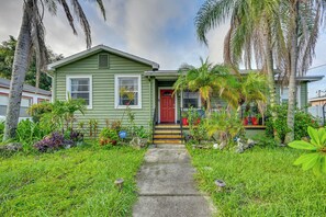 A green house with a red door, surrounded by lush greenery and palm trees. - < 2 Mi to Raymond James Stadium! Couple’s Retreat (Tampa)
