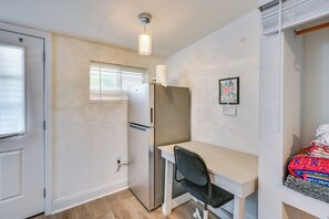 A compact room with a kitchenette, a single bed with a colorful blanket, a small desk, and a window with blinds. - < 2 Mi to Raymond James Stadium! Couple’s Retreat (Tampa)