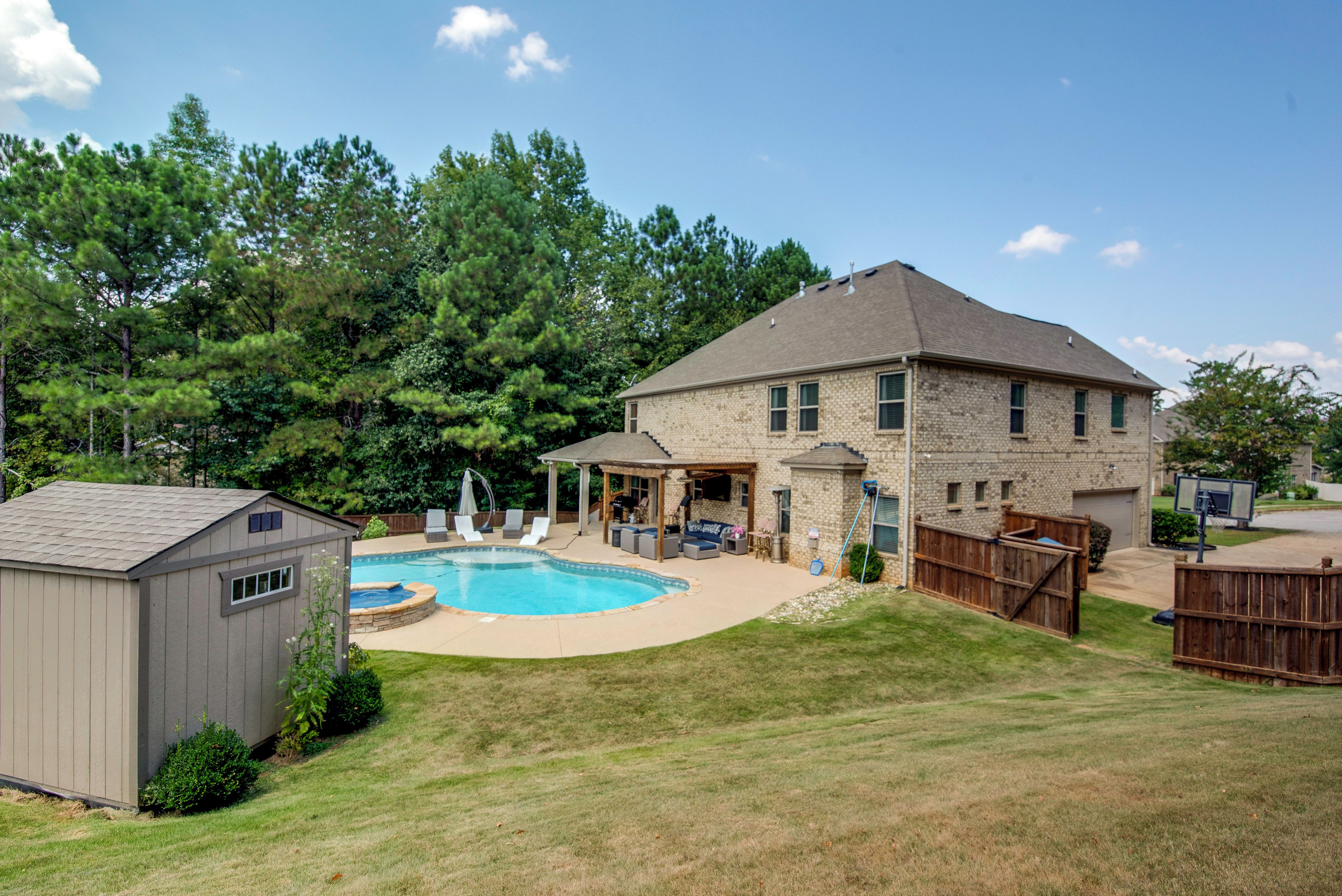 A residential backyard with a swimming pool, a covered patio, and a detached garage.