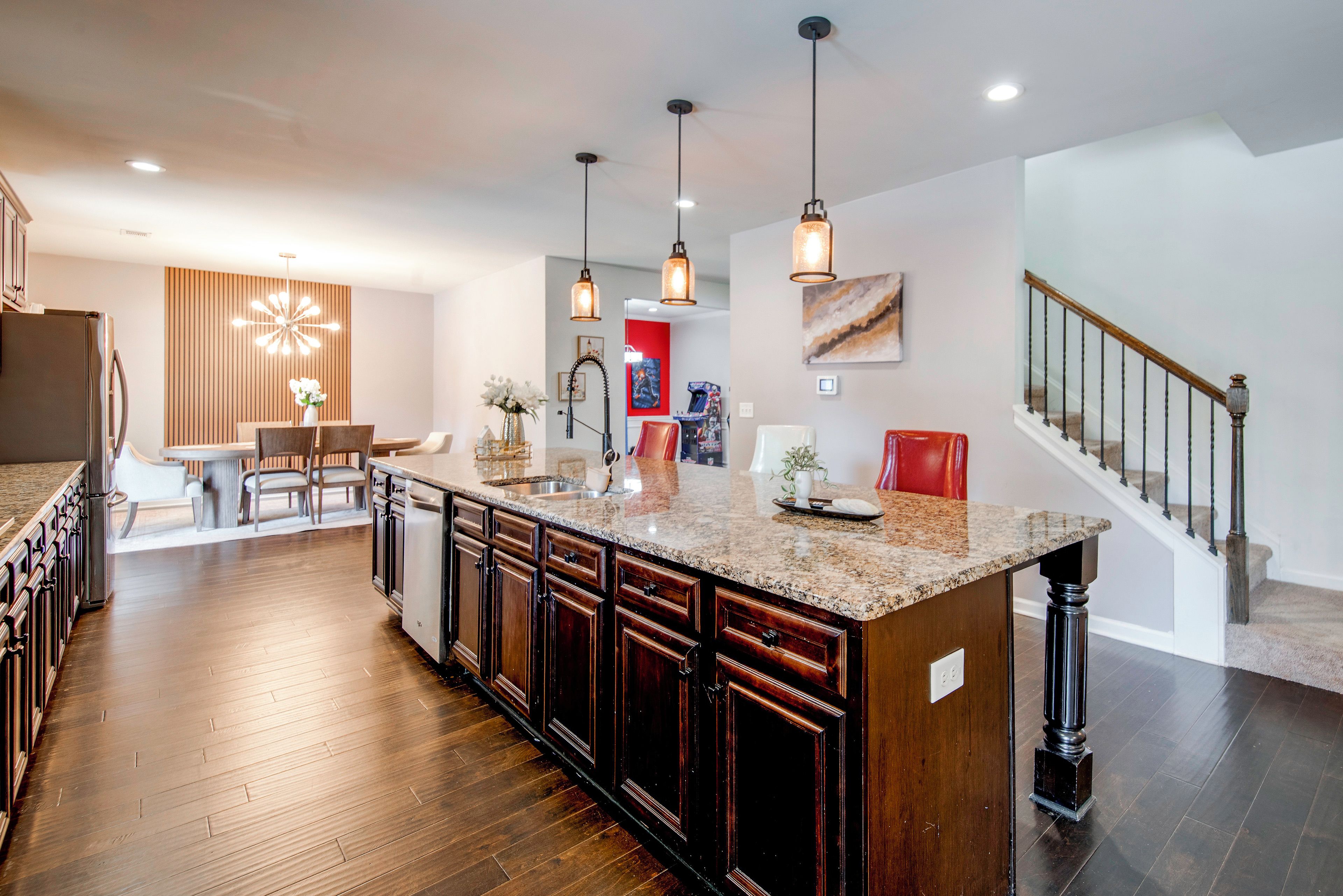 A modern kitchen with a large island, wooden cabinets, and pendant lighting.