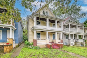 A two-story house with a porch and a small garden area. - Easy Niagara Falls Access! Apt w/ Full Kitchen (Niagara Falls)