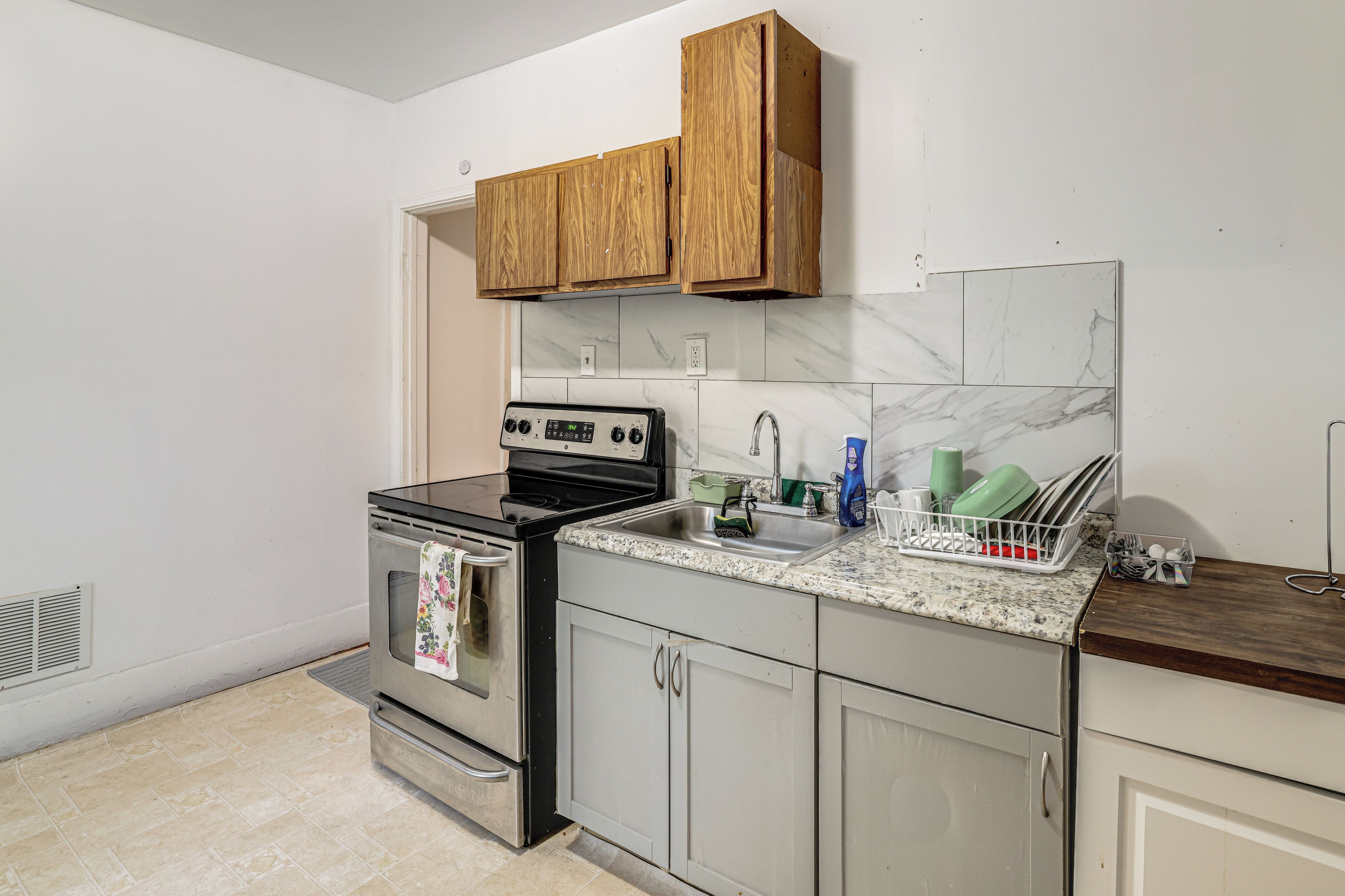 Una cocina con estufa, lavamanos y armarios de madera.