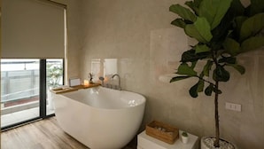 Casa de banho moderna com uma banheira independente, uma grande planta em vaso e vista para o exterior através de uma porta deslizante.