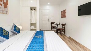 Quarto de hotel com cama, guarda-roupa, área de estar e televisão.