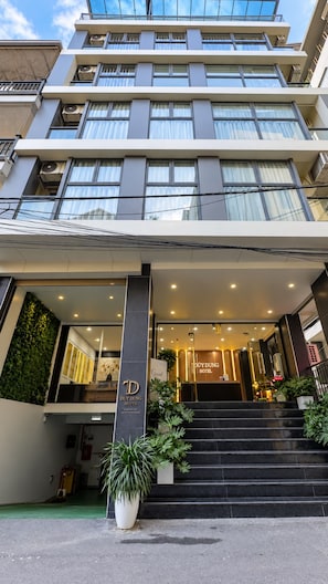 A hotel entrance with a modern design, featuring a staircase leading to the lobby, a reception desk, and a sign indicating the hotel name. - Thuy Dung Hotel (Tu Liem)