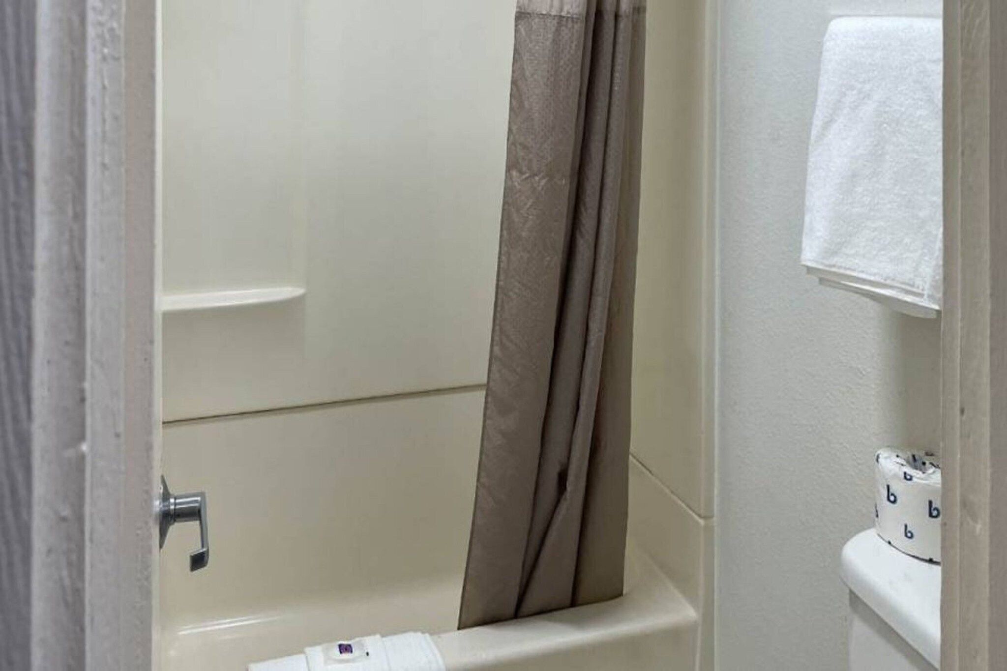 A bathroom with a bathtub, a shower curtain, a towel rack, and a toilet.