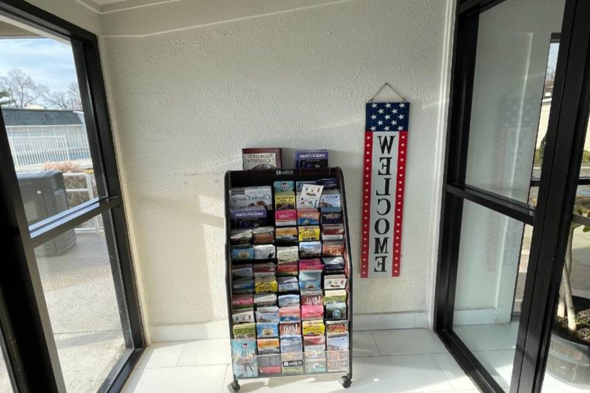 A display rack with various travel books and a 'WELCOME' sign with an American flag design.