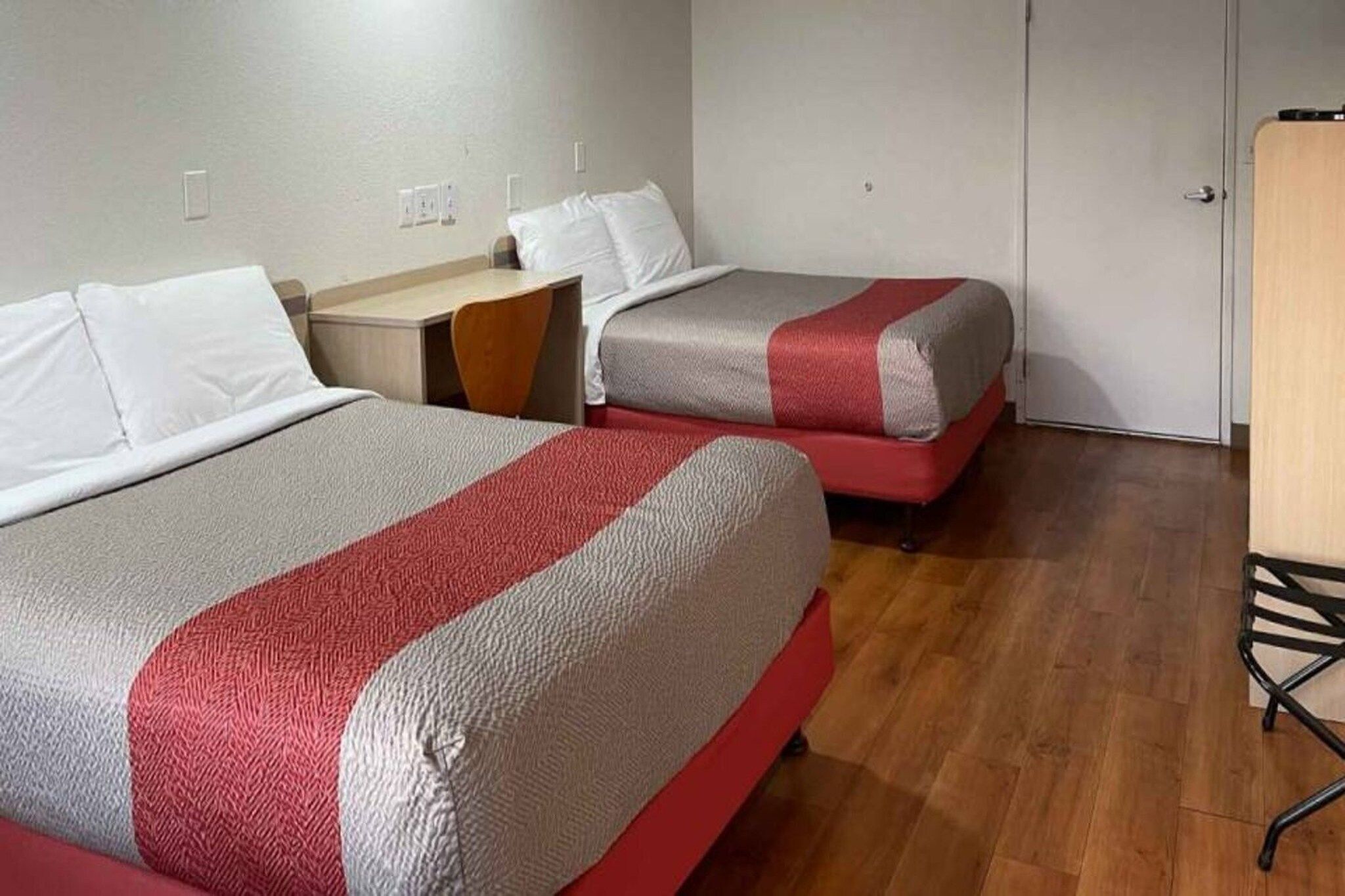 A room with two beds, a desk, and a chair.