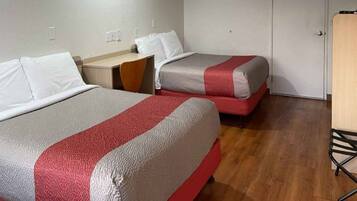 A room with two beds, a desk, and a chair.