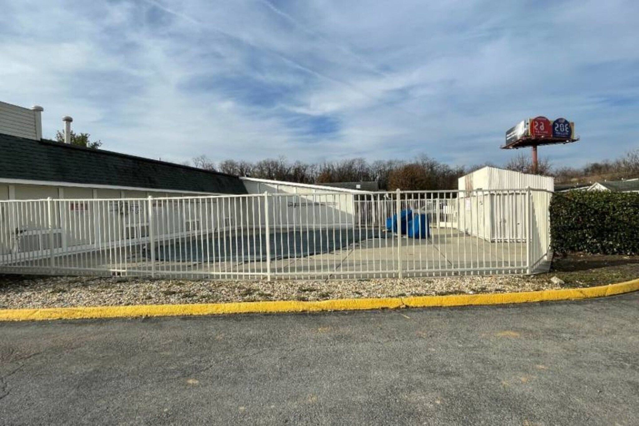 A fenced parking area with a building in the background.