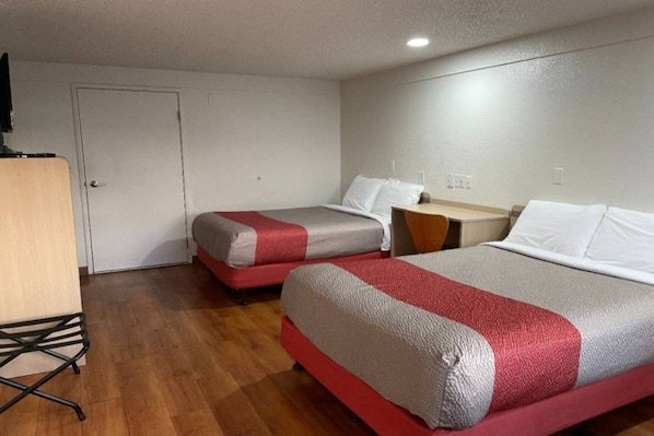 Quarto de hotel com duas camas, uma escrivaninha e uma cadeira.