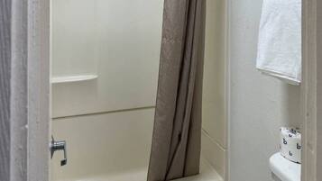 A bathroom with a bathtub, a shower curtain, a towel rack, and a toilet.