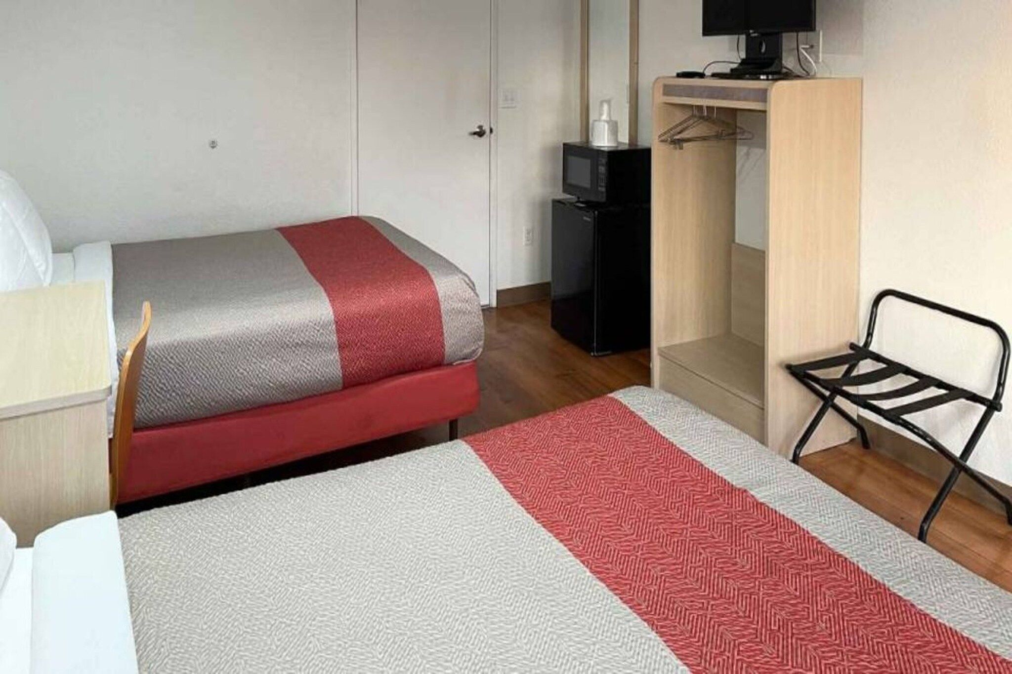 Una habitación de hotel con una cama, un escritorio, un televisor y un armario.
