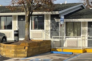 Um motel com construção térrea, varanda coberta e área de estacionamento.
