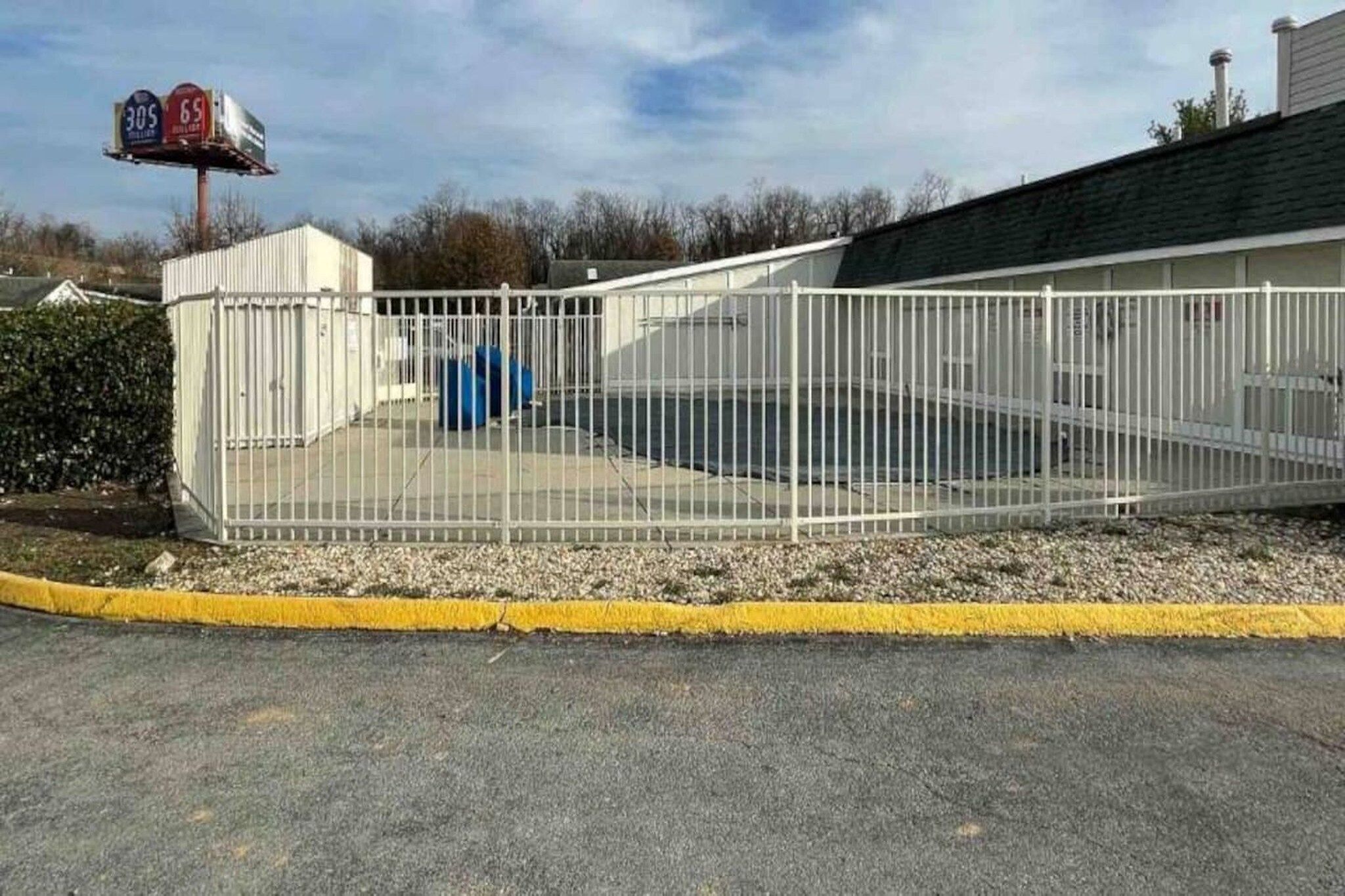 A fenced parking area with a building in the background.