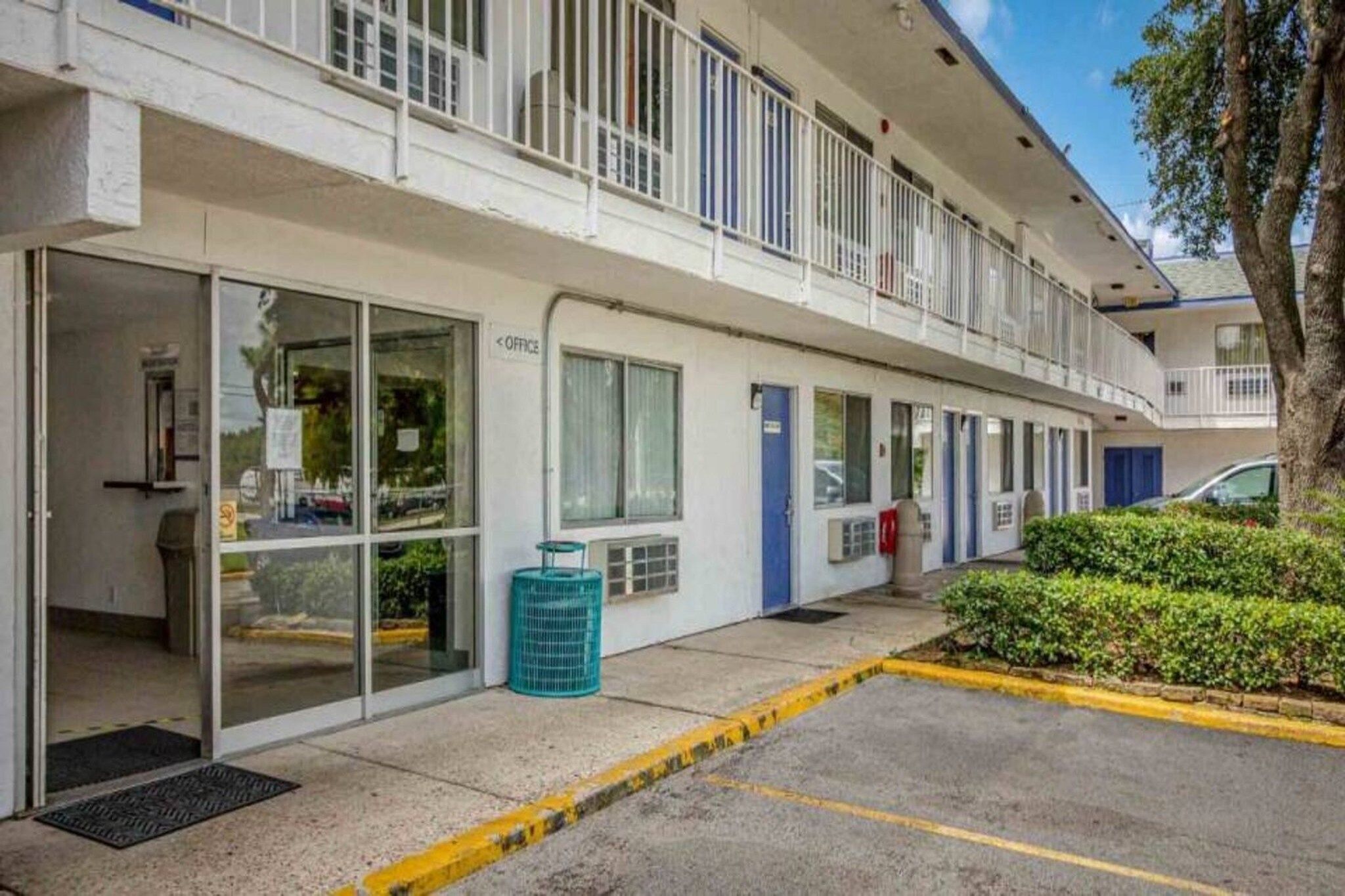 Un edificio con varias puertas, algunas con letreros, y una puerta azul con un buzón rojo.
