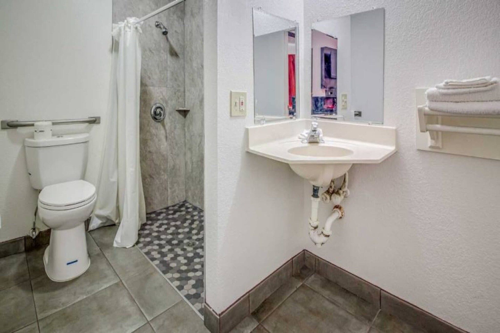 Un baño con inodoro, ducha, lavamanos y espejo.