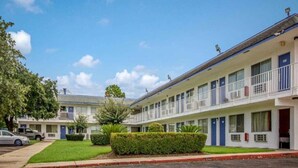 Un motel con una fila de habitaciones, cada una con un balcón y una puerta numerada.
