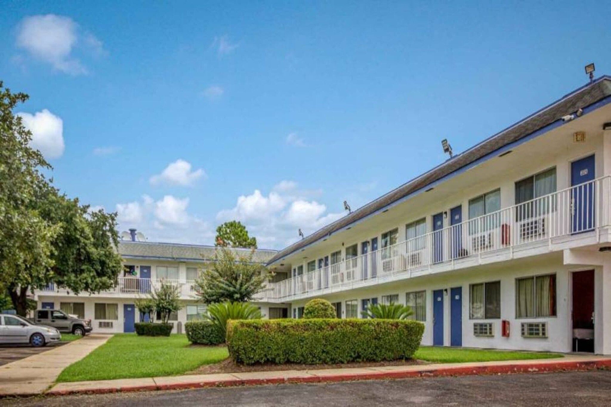 A motel with a two-story structure, multiple rooms, and a parking area.