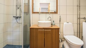 A bathroom with a glass shower enclosure, a wooden vanity with a sink and mirror, and a toilet. - Viinijärvi d 9 by Interhome (Liperi)