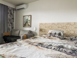 Una habitación de hotel con una cama, una silla, una lámpara y un cuadro en la pared.