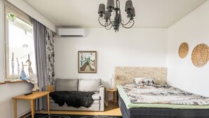 A bedroom with a sofa, a bed, a table, a chandelier, and a window with curtains. - Viinijärvi d 9 by Interhome (Liperi)