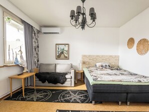 Un dormitorio con sofá, cama, mesa, candelabro y ventana con cortinas.