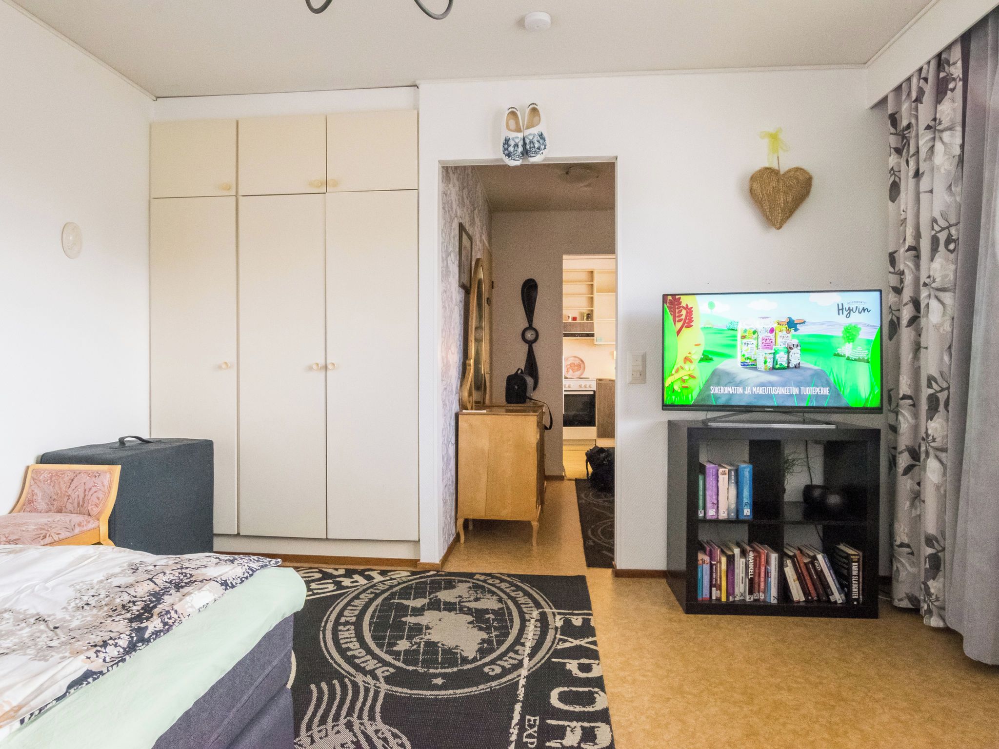 Makuuhuone, jossa on sänky, televisio, kirjahylly ja vaatekaappi.