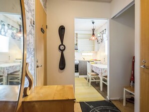 Un pasillo con una mesa de madera, un reloj de pared y una zona de cocina con una mesa de comedor y sillas.