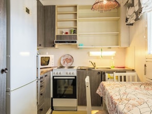 Una kitchenette compacta con microondas, estufa y lavabo.