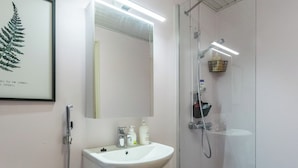 A modern bathroom with a glass shower enclosure, a white sink, and a framed fern artwork on the wall. - Viinijärvi d 10 by Interhome (Liperi)
