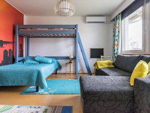 Una habitación con literas, un sofá, una mesita y una ventana con cortinas.