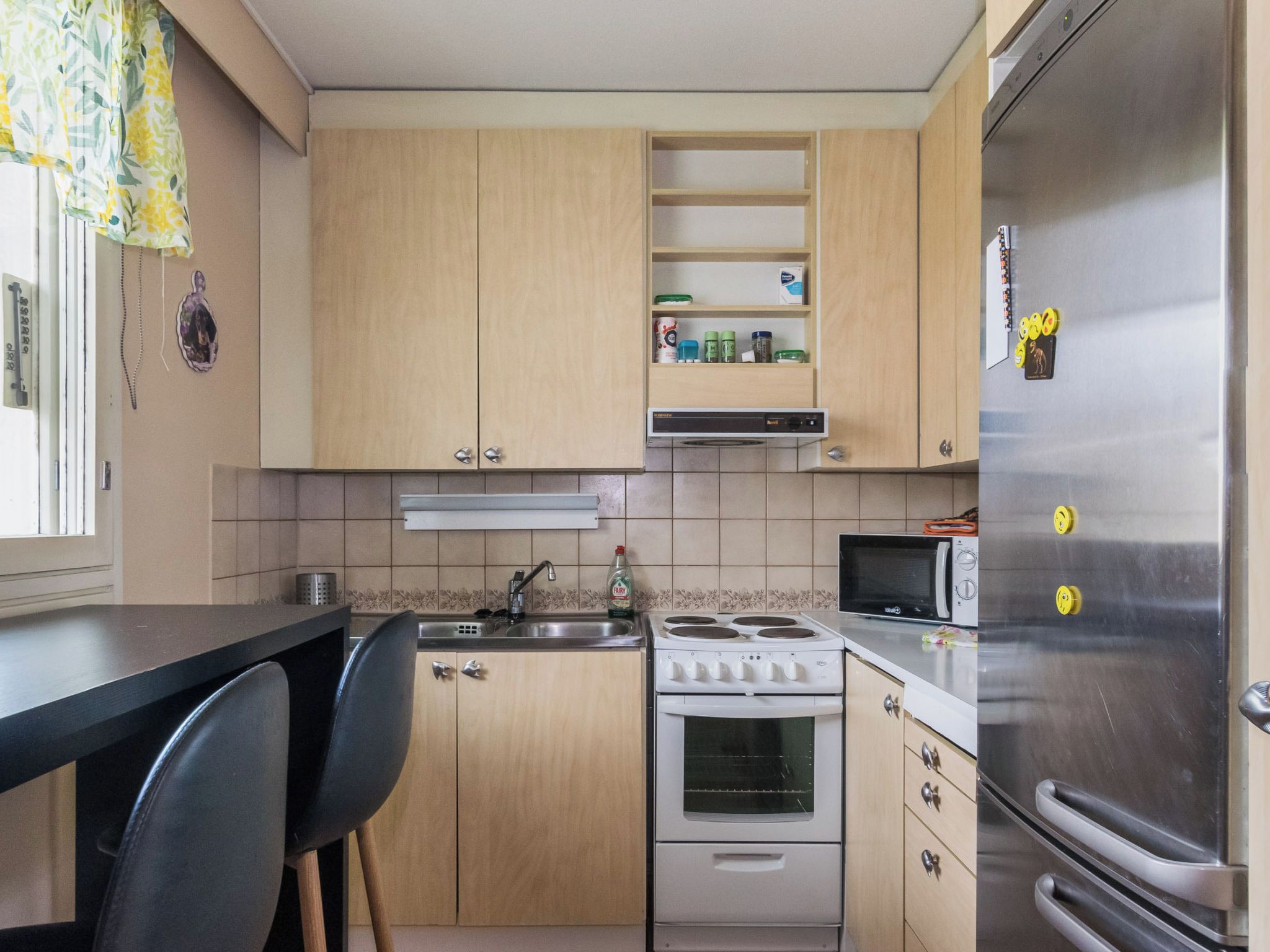 Een kleine keuken met een fornuis, magnetron en koelkast.