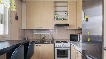 Een kleine keuken met een fornuis, magnetron en koelkast.