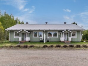 A two-story building with a metal roof, two porches with steps, and a gravel driveway.