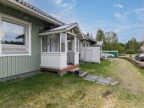 En etagers bygning med veranda, overdækket terrasse og en lille have.