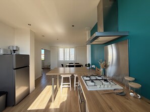 A modern kitchen with a stainless steel refrigerator, a wooden dining table, and a gas stove. - Spacious & Bright Apartment - Sleeps 6 - Rochefort (Rochefort)